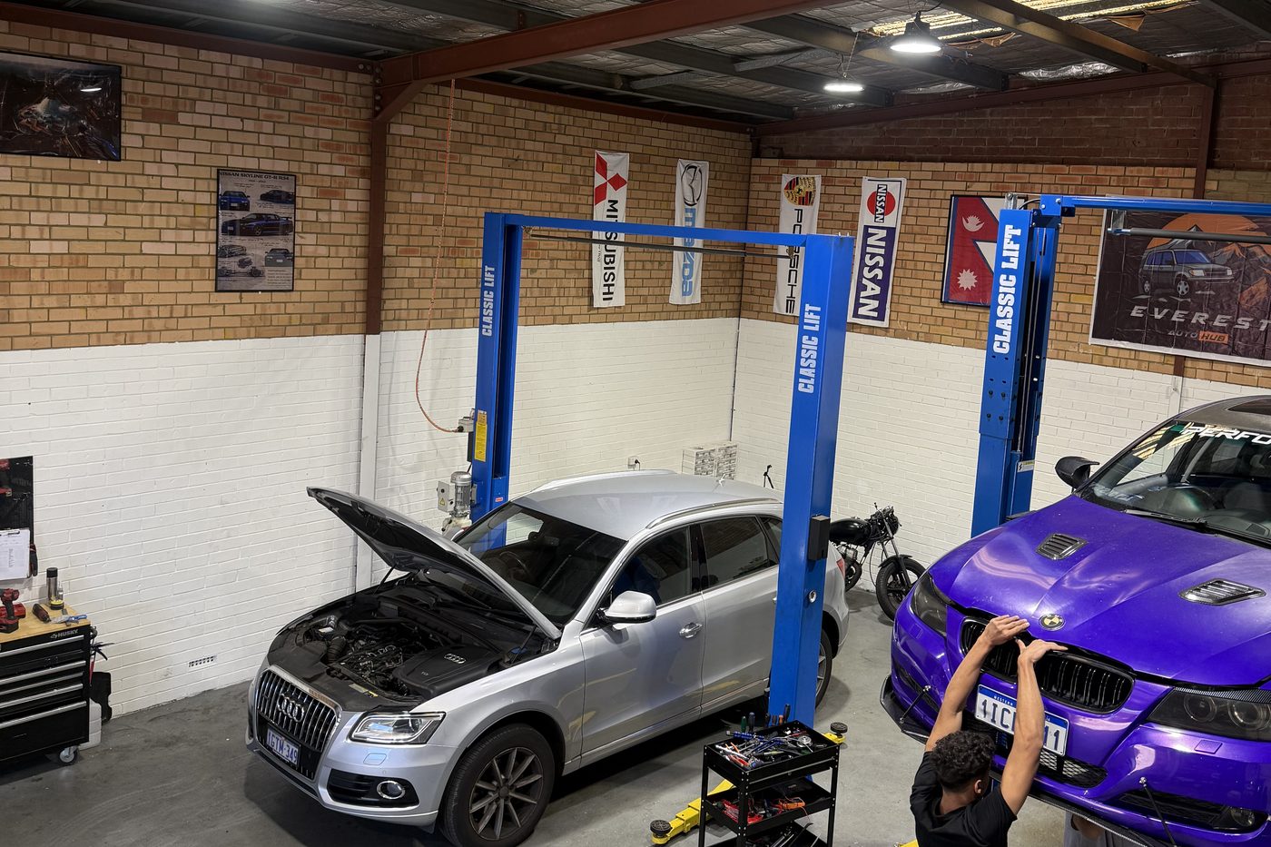 Two cars raised on the hoists inside the Everest Auto Hub workshop in Bayswater