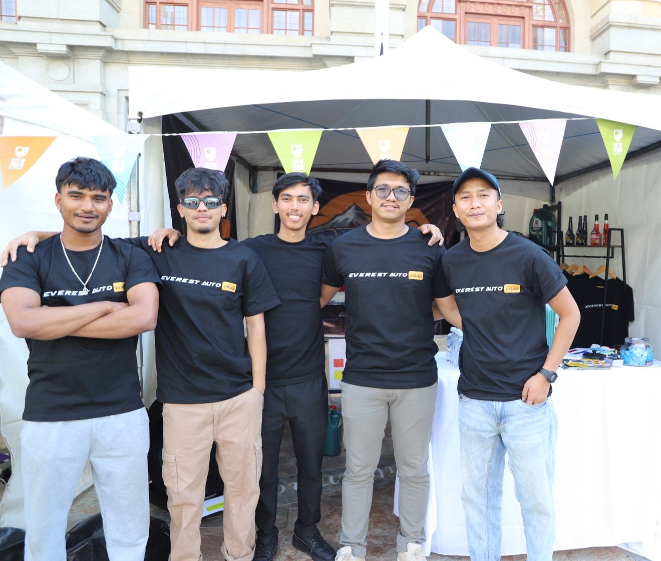 The Everest Auto Hub team in branded shirts beside their services banner at a community event in Perth