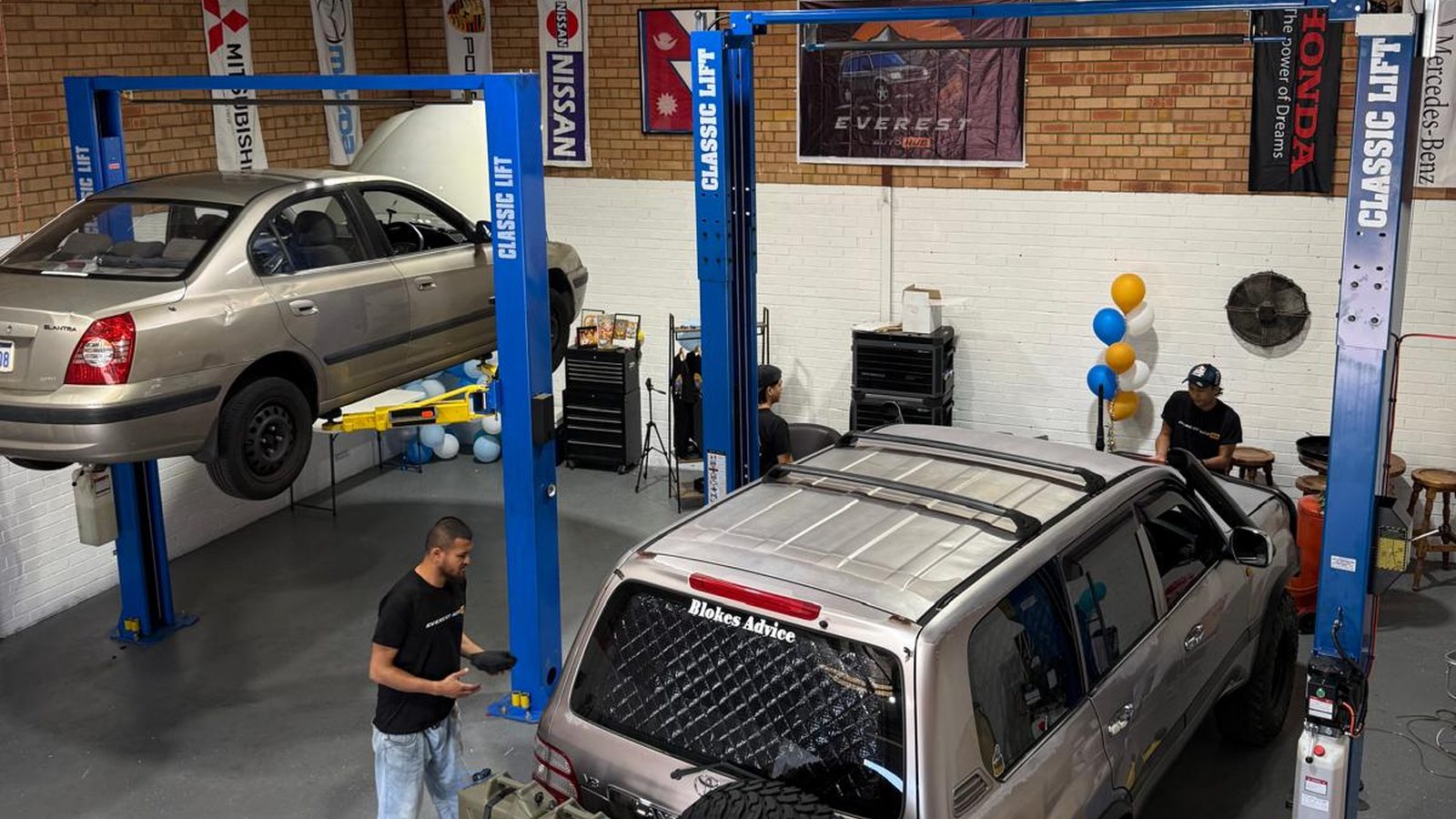 A wide view of the Everest Auto Hub workshop floor with vehicles on both hoists